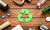 Différents types de matières recyclables sur une table, avec le logo recyclage vert en son centre.