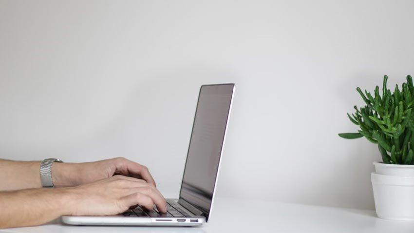 Un homme tape sur le clavier d'un ordinateur portable.